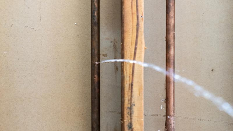 Plumber inspecting aging pipes under a sink, illustrating common hidden plumbing issues during home inspections